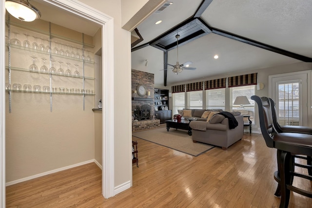 living room with wood finished floors, ceiling fan, baseboards, and vaulted ceiling with beams