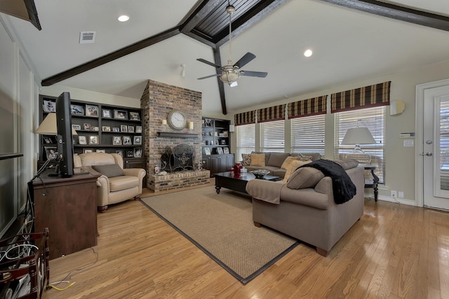 living room with a fireplace, light wood-style flooring, a ceiling fan, visible vents, and vaulted ceiling with beams