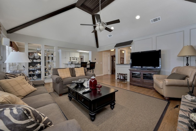 living area featuring visible vents, ceiling fan, beam ceiling, and wood finished floors