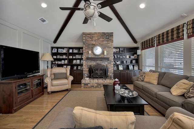 living area featuring lofted ceiling with beams, a fireplace, a ceiling fan, visible vents, and light wood finished floors