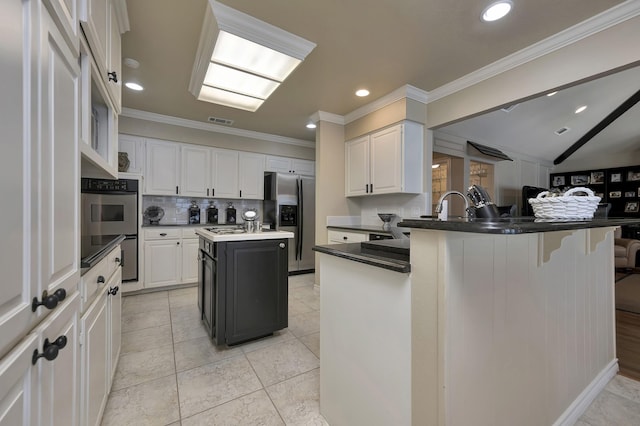 kitchen with ornamental molding, a peninsula, a center island, backsplash, and stainless steel appliances
