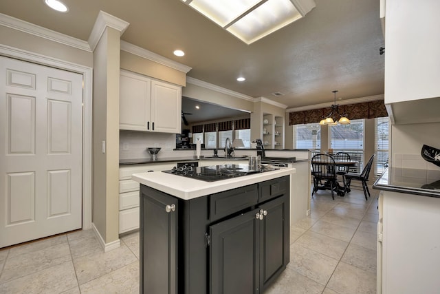 kitchen featuring a sink, crown molding, white cabinetry, black electric stovetop, and a kitchen island