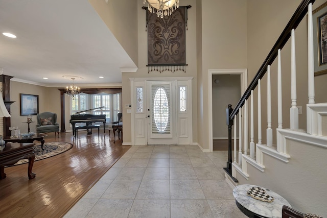 entryway featuring crown molding, an inviting chandelier, baseboards, and stairway
