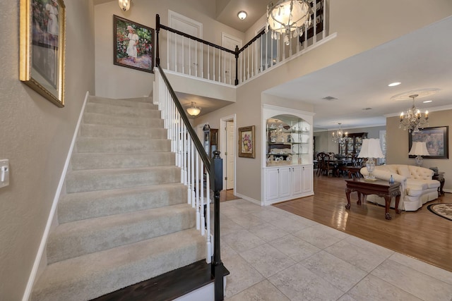 stairs with baseboards, a chandelier, tile patterned floors, a high ceiling, and visible vents