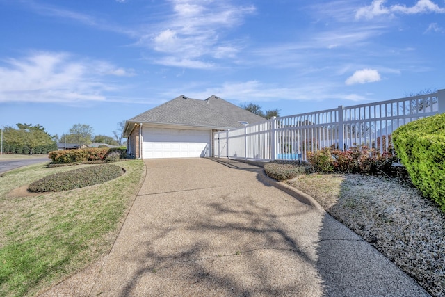 view of property exterior with concrete driveway, a garage, a yard, fence, and a shingled roof