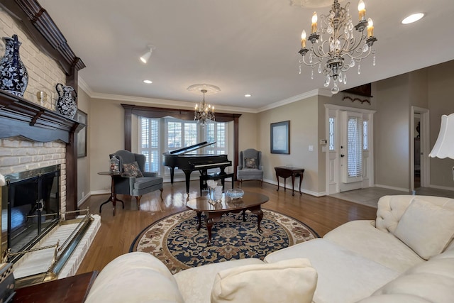 living room featuring a notable chandelier, baseboards, a fireplace, crown molding, and wood finished floors