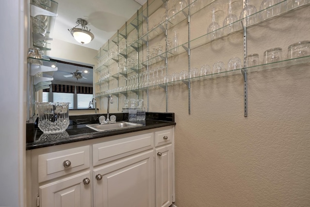 bar with a textured wall, a sink, and wet bar