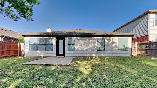 rear view of house featuring a shingled roof, a fenced backyard, a patio area, and a lawn
