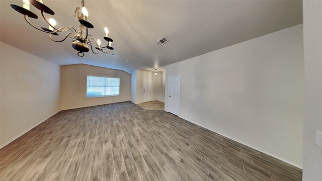 interior space featuring baseboards, an inviting chandelier, a textured ceiling, visible vents, and wood finished floors