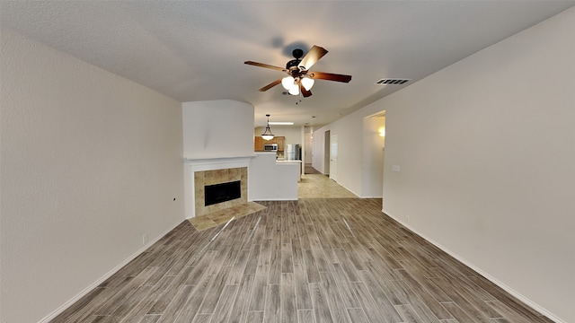 unfurnished living room featuring a fireplace, light wood-style flooring, baseboards, and ceiling fan
