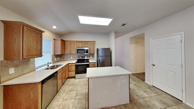 kitchen with visible vents, a sink, vaulted ceiling, stainless steel appliances, and backsplash