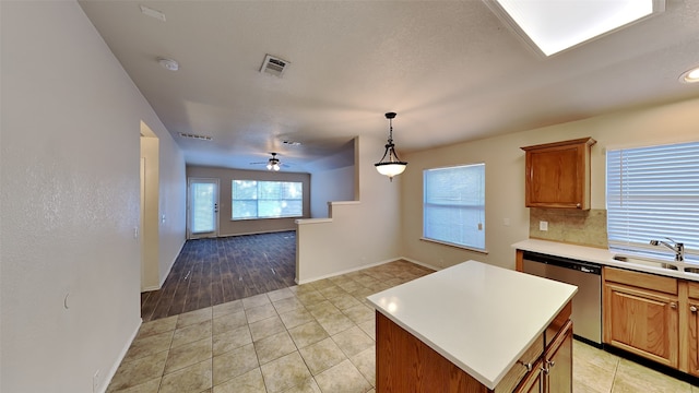 kitchen with visible vents, a kitchen island, dishwasher, light countertops, and a sink