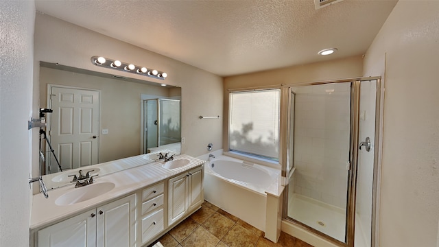 full bath with a sink, a textured ceiling, a stall shower, and a garden tub