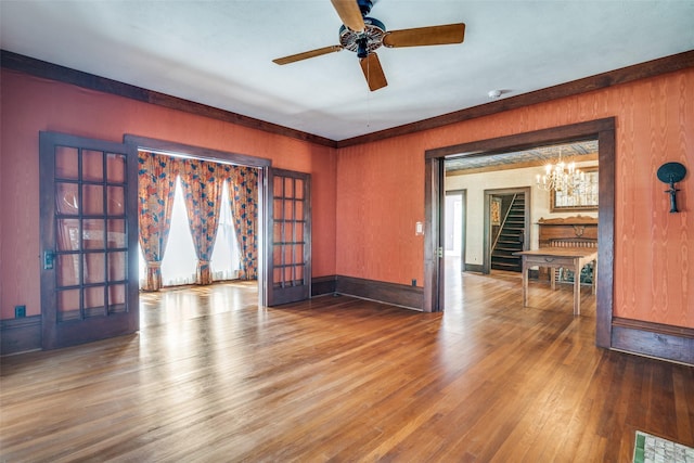 401 Pacific Ave, Terrell, TX 75160 - empty room featuring baseboards, stairway, wood finished floors, ceiling fan with notable chandelier, and french doors