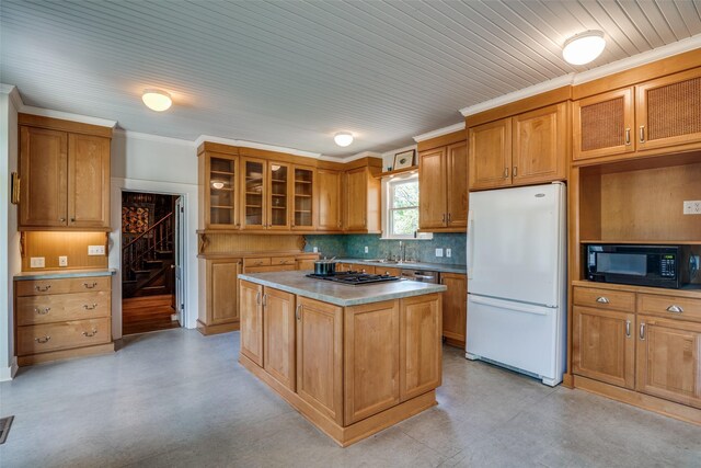 401 Pacific Ave, Terrell, TX 75160 - kitchen with tasteful backsplash, ornamental molding, black microwave, freestanding refrigerator, and stainless steel gas stovetop