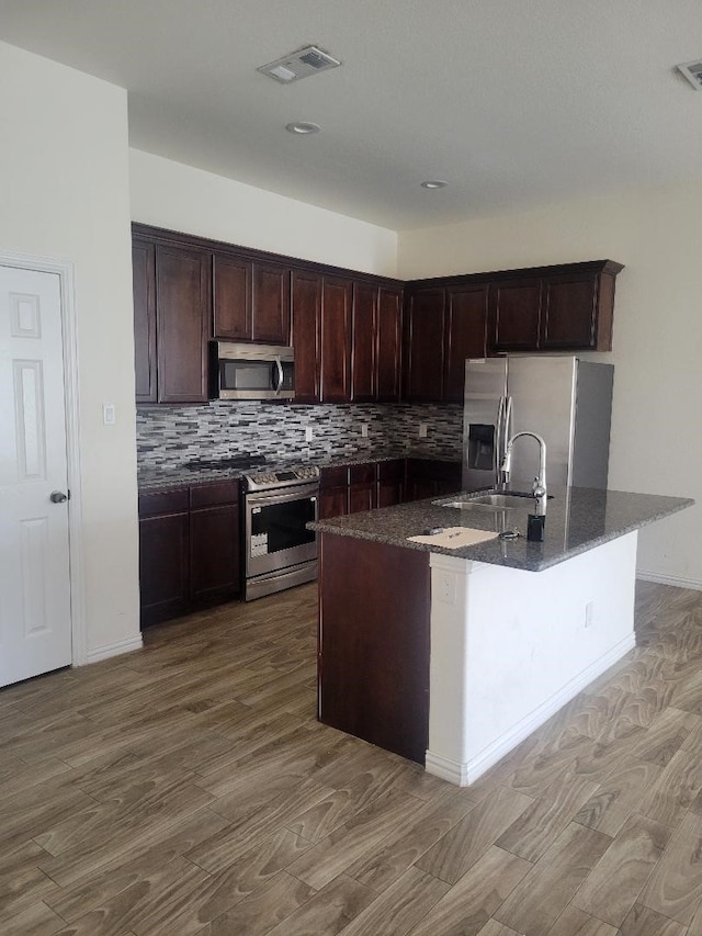 14247 Greenhaw Ln, Dallas, TX 75253 - kitchen featuring appliances with stainless steel finishes, visible vents, decorative backsplash, a sink, and wood finished floors