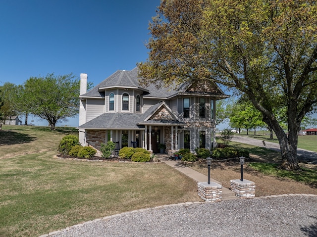 view of front facade featuring a front lawn, a shingled roof, and a chimney