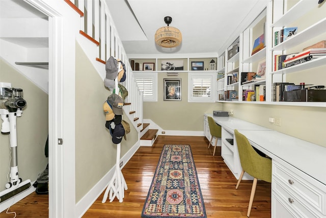 home office with baseboards, built in study area, and dark wood-type flooring