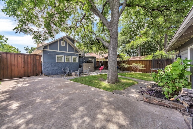 view of front of property with a patio, a trampoline, and fence