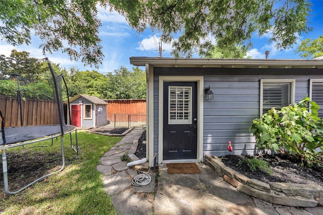 view of shed with a trampoline and fence
