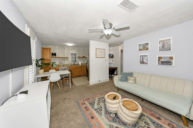 living area with light colored carpet, a ceiling fan, and visible vents