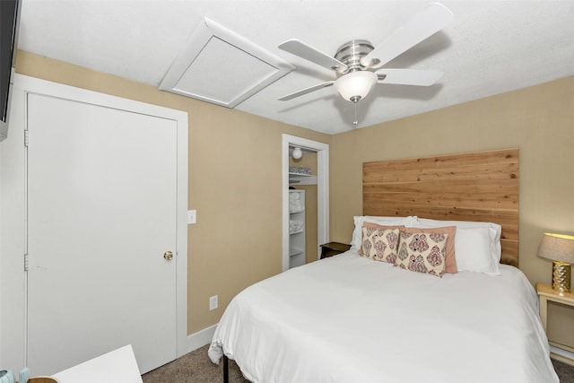 carpeted bedroom with attic access and a ceiling fan