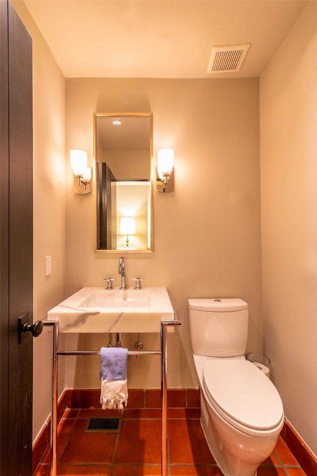 bathroom featuring toilet, visible vents, baseboards, and a sink