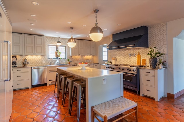 kitchen featuring premium appliances, tasteful backsplash, a center island, and wall chimney exhaust hood