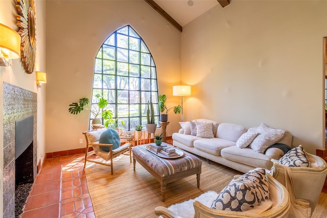 living area featuring baseboards, a fireplace, beamed ceiling, tile patterned floors, and high vaulted ceiling