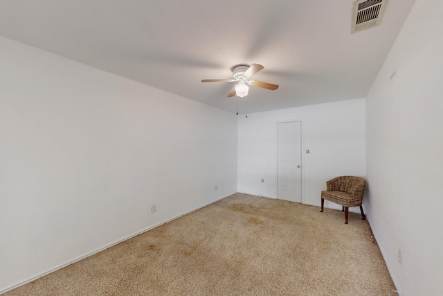 spare room featuring ceiling fan, light carpet, and visible vents