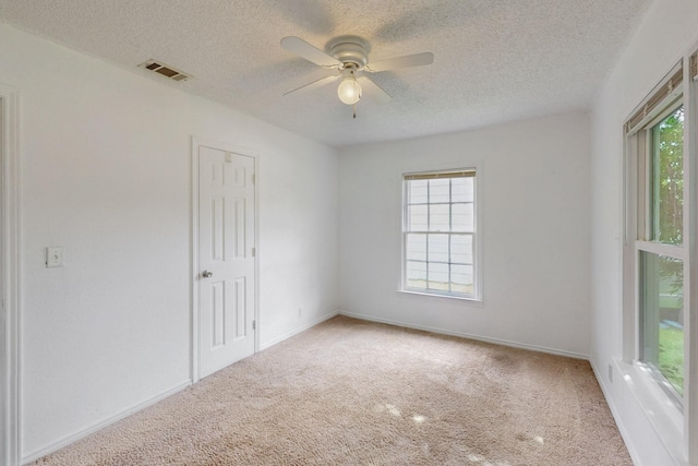 empty room featuring visible vents, baseboards, a textured ceiling, carpet flooring, and ceiling fan
