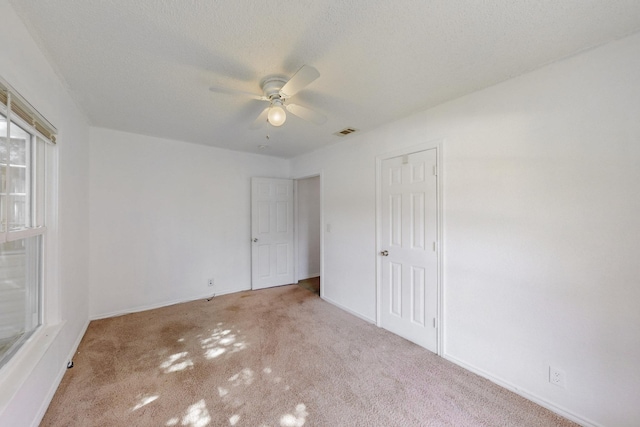 unfurnished bedroom with a textured ceiling, baseboards, visible vents, a ceiling fan, and carpet floors