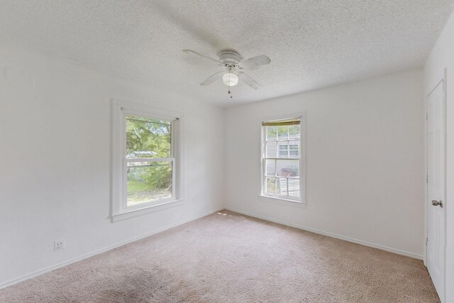empty room featuring a textured ceiling, carpet flooring, a ceiling fan, and baseboards