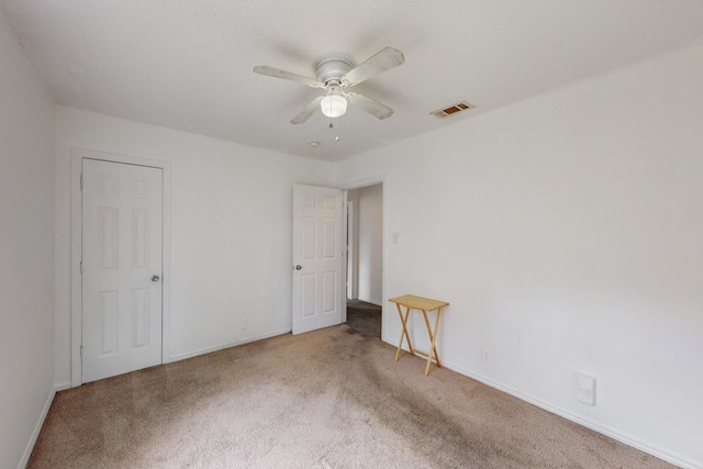 unfurnished bedroom featuring baseboards, visible vents, carpet, and ceiling fan