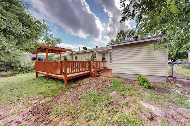 rear view of house featuring fence, a wooden deck, and a lawn