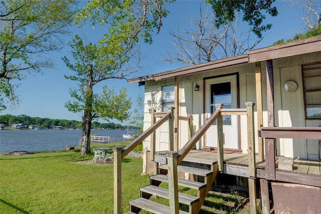 doorway to property with a water view and a lawn