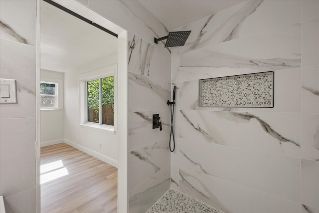 full bath with wood finished floors, baseboards, and a marble finish shower