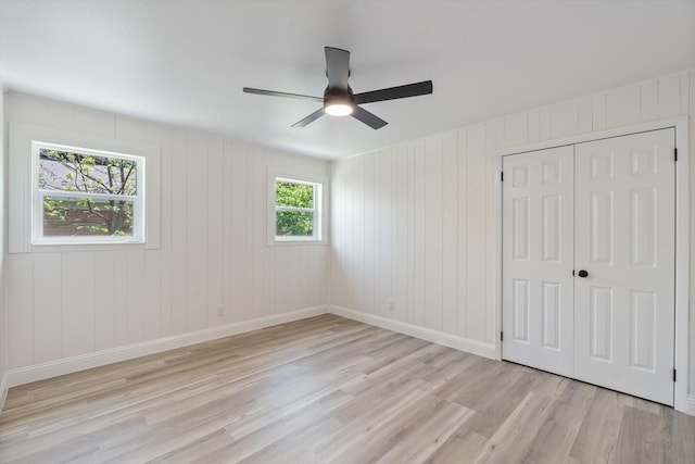 unfurnished bedroom with a closet, light wood-type flooring, baseboards, and a ceiling fan