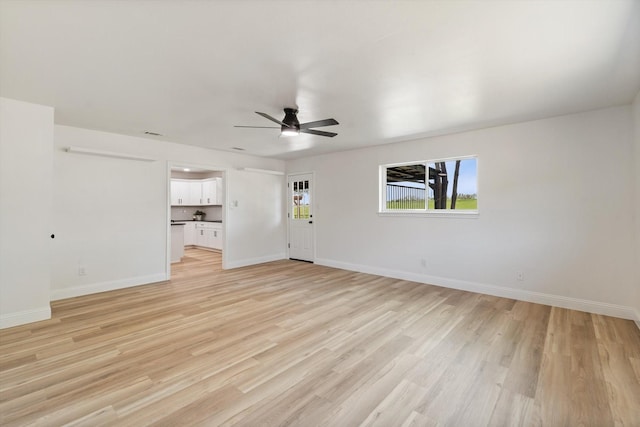 unfurnished living room with baseboards, a ceiling fan, and light wood-type flooring