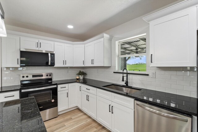 kitchen featuring stainless steel appliances, white cabinetry, a sink, and backsplash