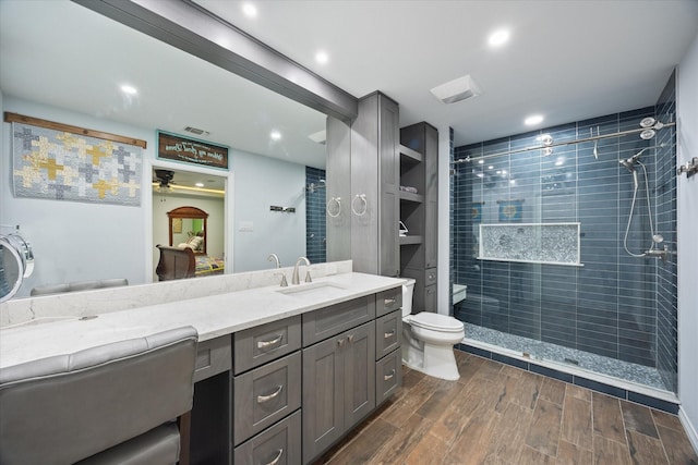 813 Grinnell Dr, Richardson, TX 75081 - bathroom with ceiling fan, toilet, tiled shower, vanity, and wood finished floors