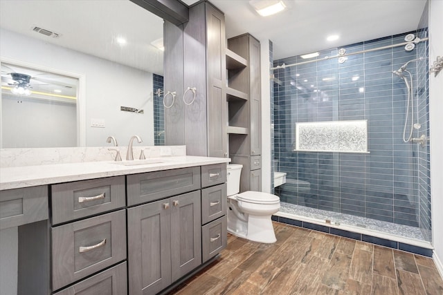 813 Grinnell Dr, Richardson, TX 75081 - bathroom featuring toilet, tiled shower, vanity, wood finished floors, and ceiling fan