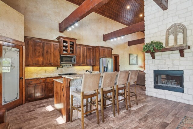 kitchen featuring appliances with stainless steel finishes, a breakfast bar, dark wood-type flooring, backsplash, and high vaulted ceiling