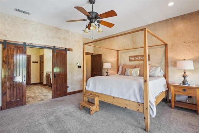 bedroom featuring visible vents, a barn door, a ceiling fan, a textured wall, and carpet floors