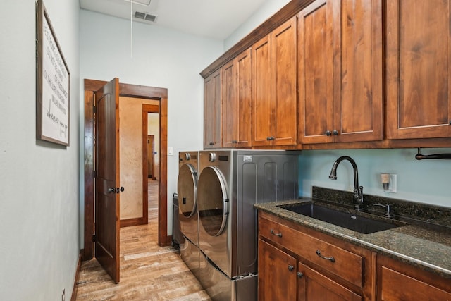 washroom with visible vents, independent washer and dryer, cabinet space, light wood finished floors, and a sink