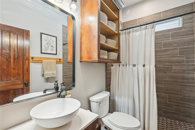 bathroom featuring toilet, a tile shower, and vanity