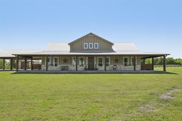 rear view of property featuring metal roof, board and batten siding, stone siding, and a lawn