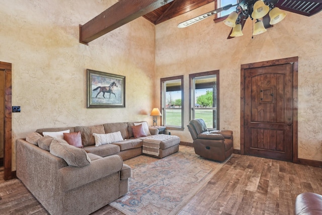 living room with high vaulted ceiling, a ceiling fan, wood finished floors, baseboards, and beam ceiling