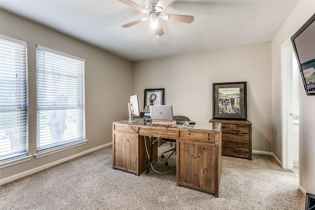 home office featuring baseboards, a ceiling fan, and light carpet