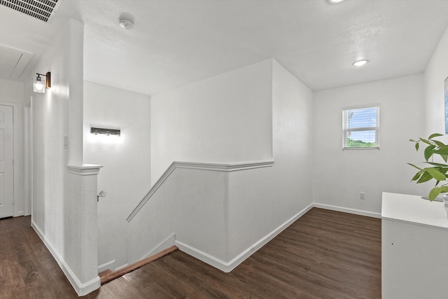 hallway with visible vents, wood finished floors, attic access, an upstairs landing, and baseboards